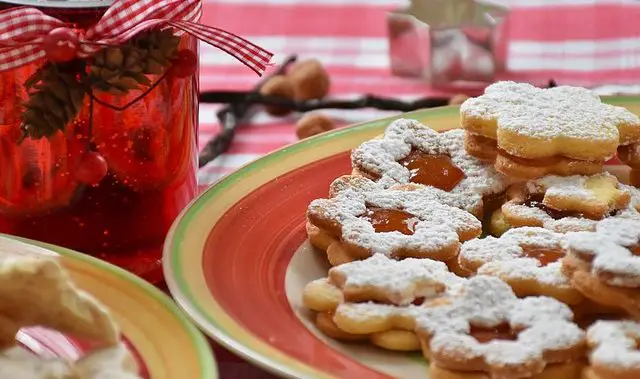 Ein Weihnachts- und Adevntsbild: Ein Teller mit Plätzchen auf einem Tisch, Ausstechformen und ein Kerzenständer