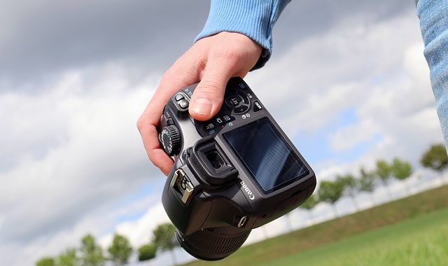 Eine Person hält in der Hand eine Spiegelreflexkamera. Symbolbild für coole Jobs und tolle Aufträge für Studenten bei Freelance Junior.