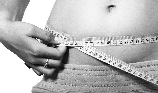 Maßband um den Bauch einer Frau. Beispielbild für den Body-Mass-Index (BMI), zu dem es neue Erkenntnisse gibt.