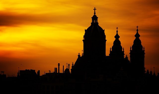 Die dunkle Silhouette einer Stadt bei Sonnenuntergang. Beispielbild für die Geschichte und Herkunft des Wortes "Silhouette".