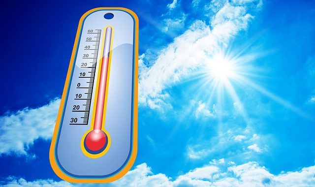 Die strahlende Sonne und ein Thermometer. Symbolbold für die Frage, ob Hitze elektronischen Geräten schadet.