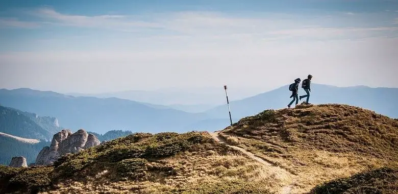 Zwei Wanderer in einer schönen Landschaft. Symbolbild für die Frage nach dem einfachen Glück mit wenig Geld.