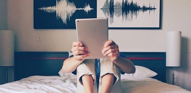Eine junge Frau sitzt auf einem Bett und liest ein E-Book. Symbolbild für das E-Book "Mo, die Piratin".