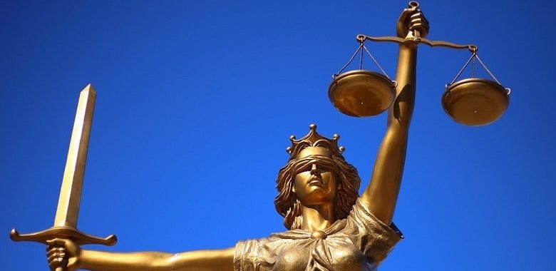 Eine Statue der Justitia, der Personifikation der Gerechtigkeit. In einer Hand hält sie eine Waage, in der anderen ein Schwert. Symbolbild für die Erklärung des Sprichworts "Auge um Auge, Zahn um Zahn".