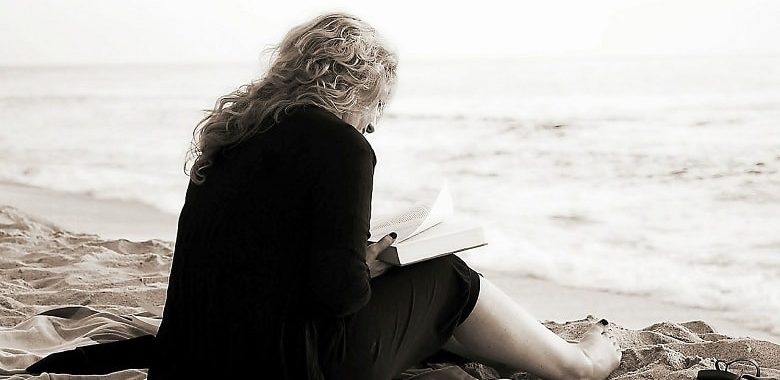Eine Frau sitzt am Strand und liest ein Buch. Symbolbild für die Lesetipps für den Mai 2017.