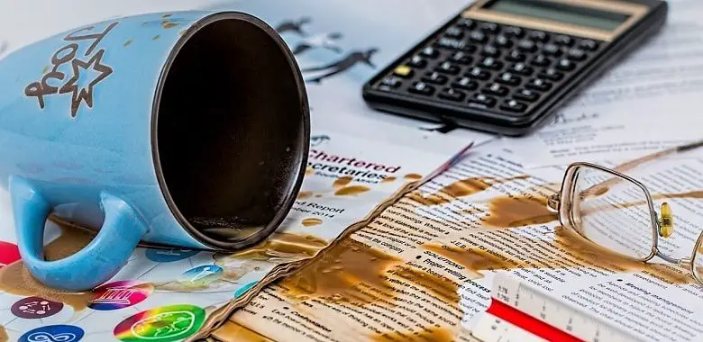 Eine umgeschüttete Kaffeetasse auf einem Schreibtisch. Symbolbild für einen Fehler und den Mut, nicht perfekt sein zu müssen.