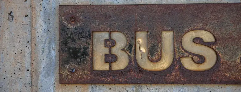 Die Großbuchstaben B, U und S auf einem verrosteten Metallschild. Symbolbild für das Textexperiment mit einem Text ohne Großbuchstaben.