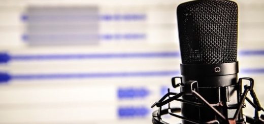 Ein Mikrophon steht vor einem Computerbildschirm. Symbolbild für die Frage, was ein Podcast ist.