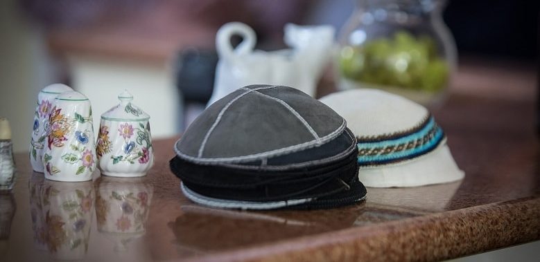 Eine Kippa liegt auf einer anderen Kippa auf einem Tisch. Die Kippa ist ein religiöses Symbol der Juden und wird hier beispielhaft für den Text verwendet, der erklärt, was Jiddisch ist.