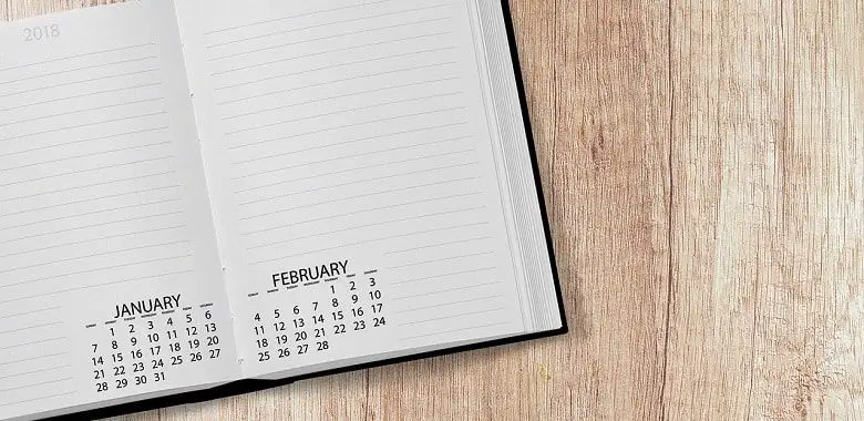Ein Kalender liegt auf einem Holztisch. Symbolbild für die Erklärung und Herkunft der Redewendung "Zwischen den Jahren".