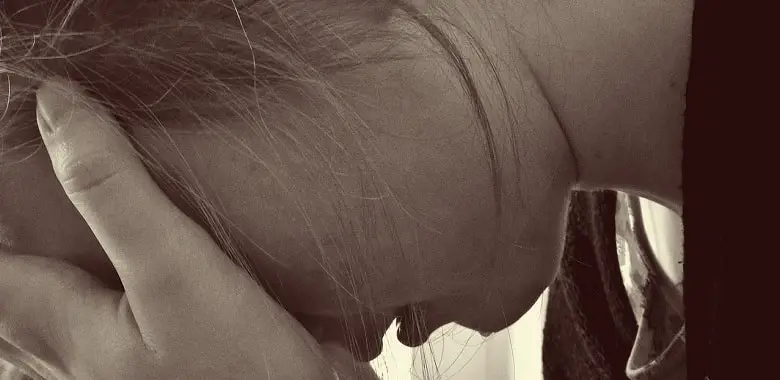 Eine junge Frau schlägt verzweifelt die Hände vors Gesicht. Symbolbild für Erklärung, Herkunft und Geschichte des Wortes "elend".