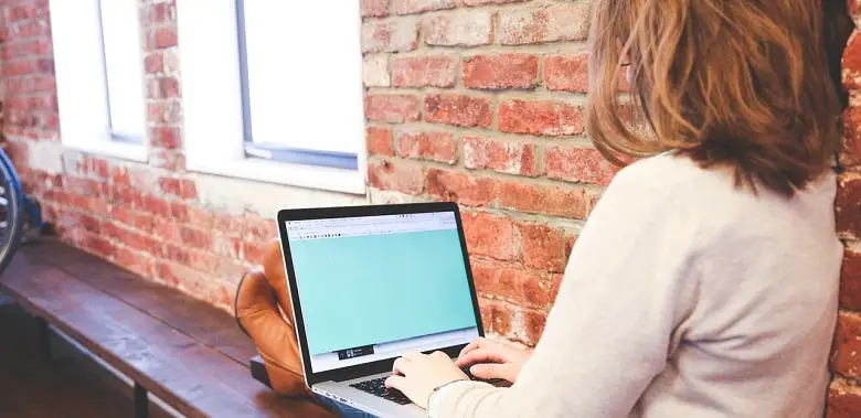 Eine Frau sitzt an einem Laptop und schreibt einen Text. Symbolbild für 100 Wörter über 100-Wörter-Texte.