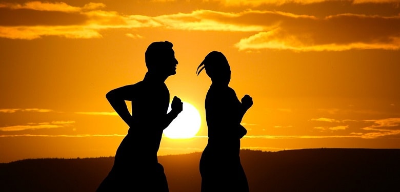 Die Silhouette zweier Jogger vor einem Sonnenuntergang. Symbolbild für 5 Tipps für Jogging-Anfänger.