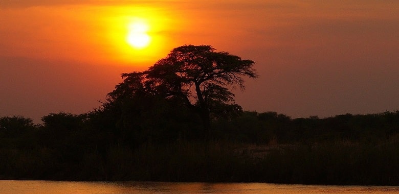 Ein Sonnenuntergang über einem Fluss in Afrika. Symbolbild für spannende Fakten über Botsuana.