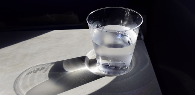 Ein Glas mit Wasser auf einem Tisch. Symbolbild für die Erklärung, ob es gefährlich ist, destilliertes Wasser zu trinken.