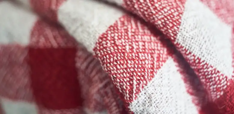 Nahaufnahme einer karierten Decke. Symbolbild für die Erklärung, was ein Plaid ist.