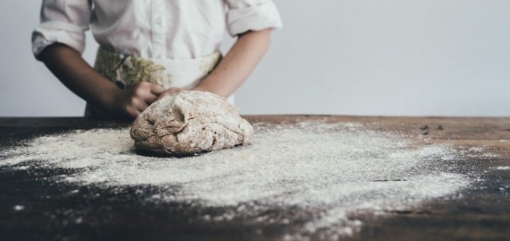 Ein gekneteter Teig liegt mit Mehl auf einem Tisch. Symbolbild für die Erklärung, was Backpulver ist und wie es funktioniert.