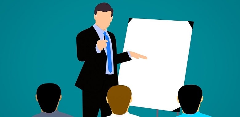 Eine Grafik, auf der eine Mann an einem Flipchart steht und anderen etwas erklärt. Symbolbild für die Vorstellung der modernen Schule mit einem Chamäleon-Klassenzimmer.