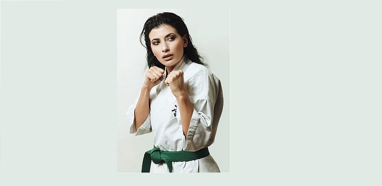 Eine Frau im Karateoutfit und mit grünem Gürtel. Symbolbild für das Schulfach der Zukunft "Selbstverteidigung".
