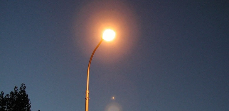 Eine Straßenlaterne leuchtet in der Nacht. Symbolbild für die Erklärung der Redensart „Licht ins Dunkel bringen“.