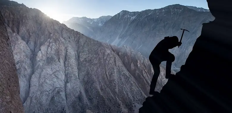 Ein Bergsteiger erklimmt einen steilen Berg. Symbolbild für die Erklärung der Redensart „Ohne Fleiß kein Preis“.