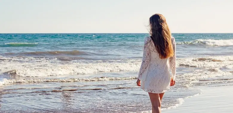 Eine Frau mit langen Haaren am Strand. Symbolbild für die Erklärung, wie schnell Haare wachsen.