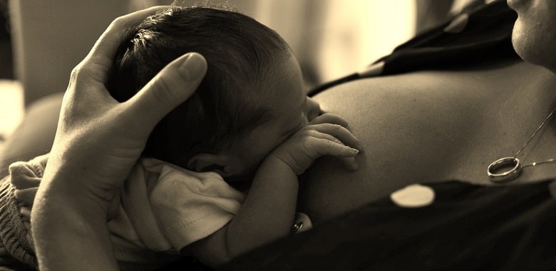 Nahaufnahme eines Babys, das gerade gestillt wird. Symbolbild für die Erklärung, ob stillende Frauen kohlensäurehaltige Getränke trinken dürfen.